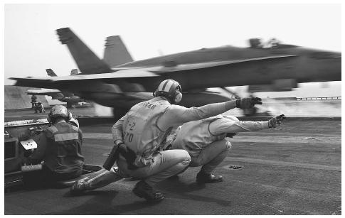 A flight deck crew gives the launch signal as an F/A-18-C Hornet is catapulted off the flight deck of the carrier USS Kitty Hawk in the Persian Gulf as part of over 3,000 American sorties flown during Operation Iraqi Freedom. AP/WIDE WORLD PHOTOS.