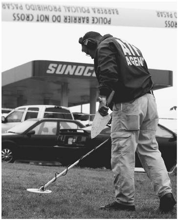 An Alcohol, Tobacco, and Firearms (ATF) agent searches for clues at a Manassas, Virginia, gas station in 2002 as part of the search for a sniper that terrorized the Washington, D.C. area. AP/WIDE WORLD PHOTOS.