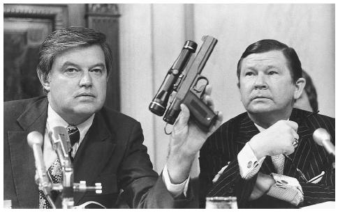 Senator Frank Church, left, chairman of the Senate Select Intelligence Committee, displays a poison dart gun as co-chairman Senator John Tower watches during the panel's probe of the activities of the Central Intelligence Agency in 1975. AP/WIDE WORLD PHOTOS.