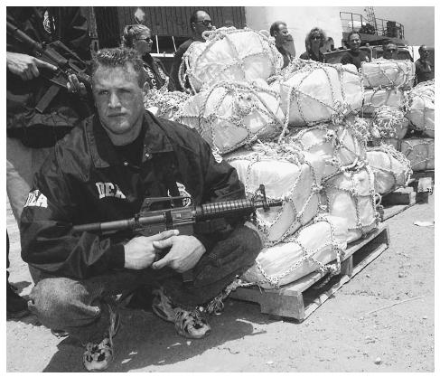 A Drug Enforcement Agency (DEA) agent stands guard next to 5,137 pounds of cocaine seized from a Panamanian vessel in Miami, Florida. AP/WIDE WORLD PHOTOS.