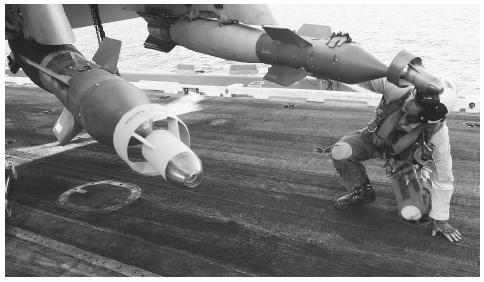 A U.S. Navy pilot inspects the laser guided weapons aboard his F/A-18C Hornet prior to his mission from the aircraft carrier USS Theodore Roosevelt. AP/WIDE WORLD PHOTOS.