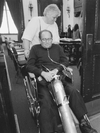 A man with emphysema is wheeled from a courtroom by his wife. He is part of a class-action lawsuit against cigarette companies. (Reproduced by permission of AP/Wide World Photos)