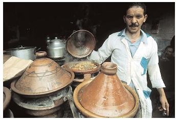 North African cuisine reflects the Islamic traditions of the region. Here, a man cooks with traditional Moroccan tajines, conical clay pots used for lamb stews and curries. [Photograph by Owen Franken. Corbis. Reproduced by permission.]