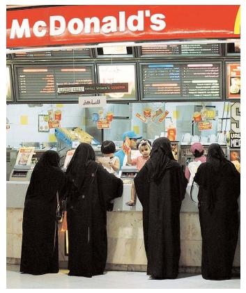 Abaya-wearing women in Saudi Arabia wait in the ladies-only line to order a quick meal. In developing nations, the popularity of fast-food alternatives to traditional cuisines has prompted debate over the nutritional and cultural impacts of Westernization. [Photograph by Saleh Rifai. AP/Wide World Photos. Reproduced by permission.]