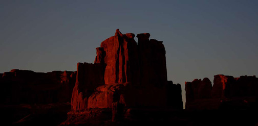 A pre-dawn Alpenglow has turned the rock formations aglow in reddish hues.